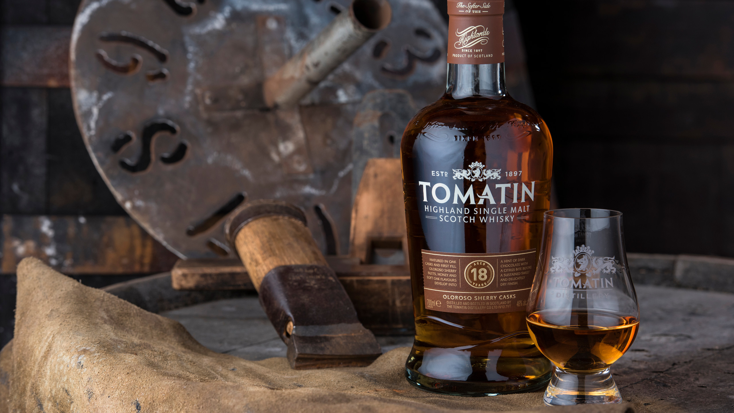 A bottle of Tomatin Scotch Whisky on a barrel with vintage tools