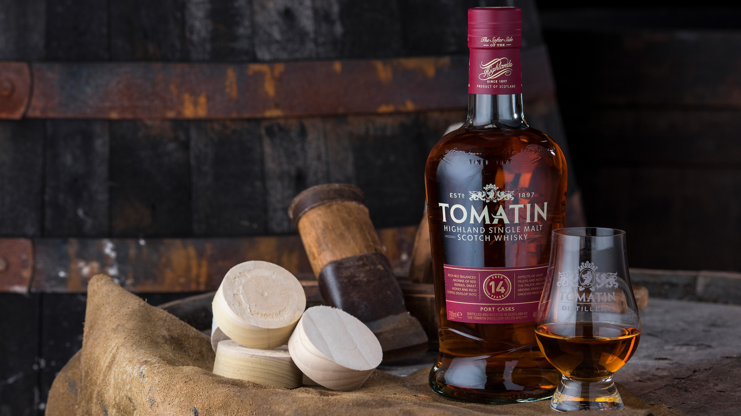 A bottle of Tomatin Whisky on a barrel with some wood disks