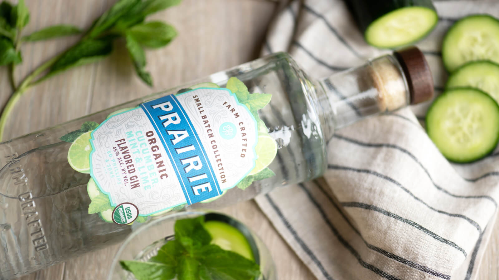 A top down view of a bottle of prairie organic spirits with cucumber slices
